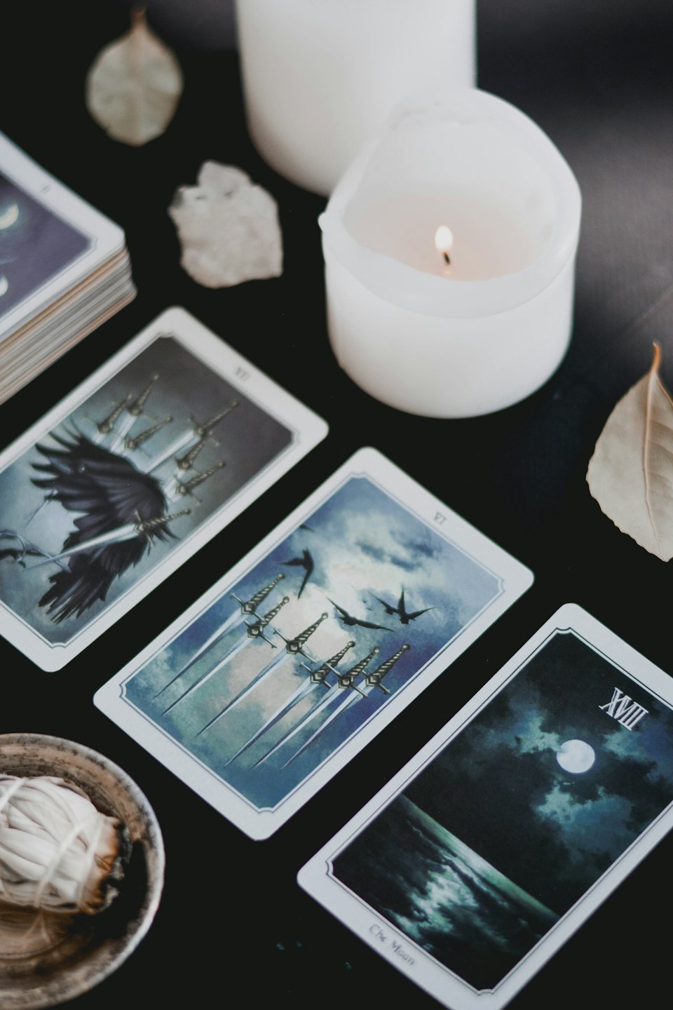 Tarot cards, sage, and candles laid out for a ritual.