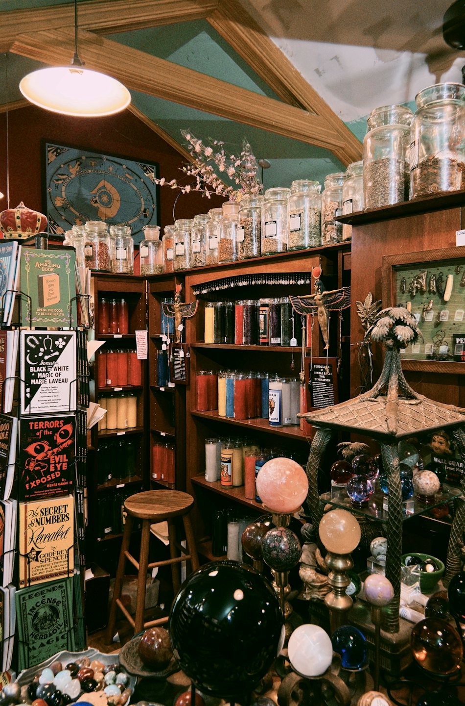 Wooden shelves filled with herbs, candles, and occult books.