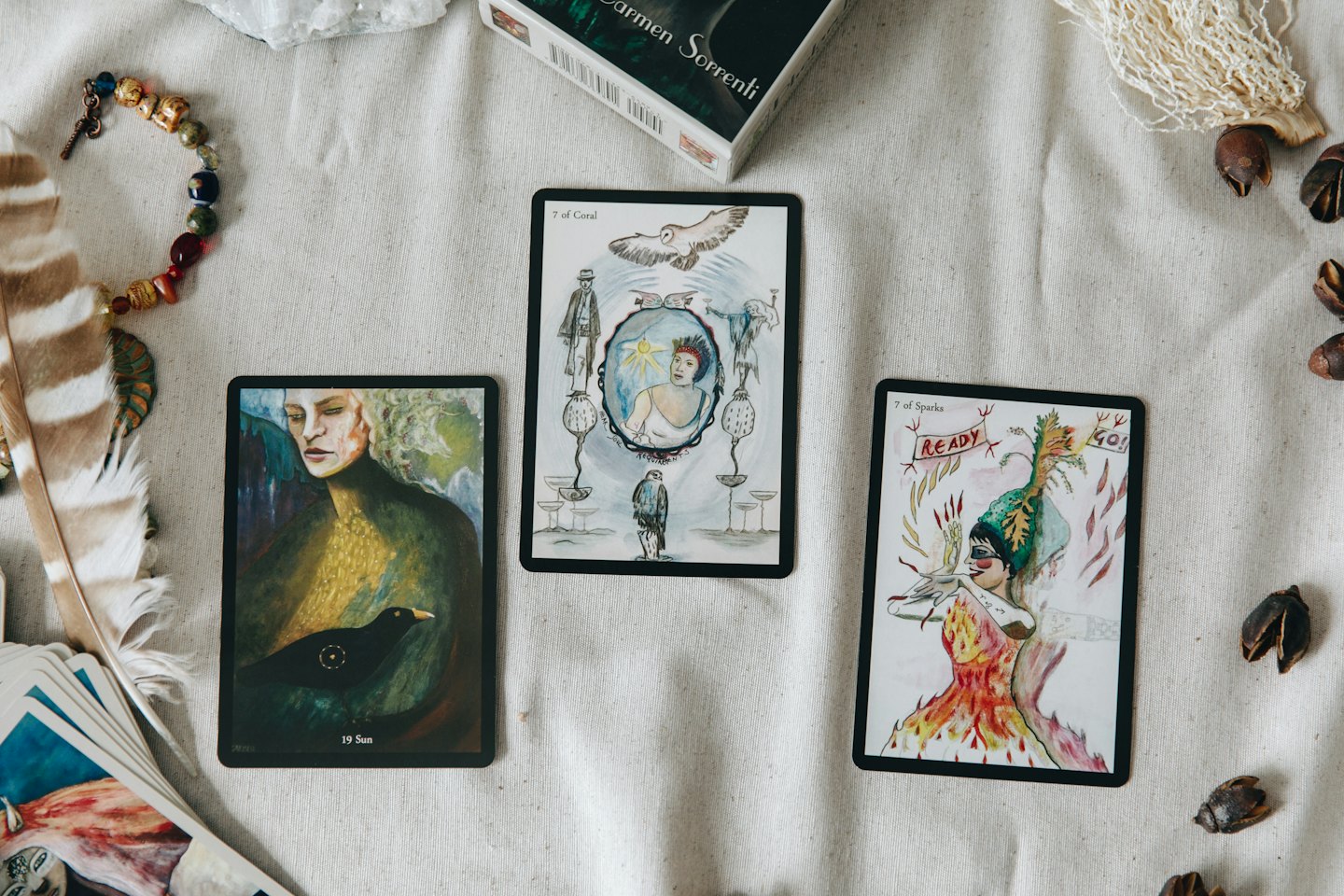 Three mystical oracle cards with crystals and feathers.